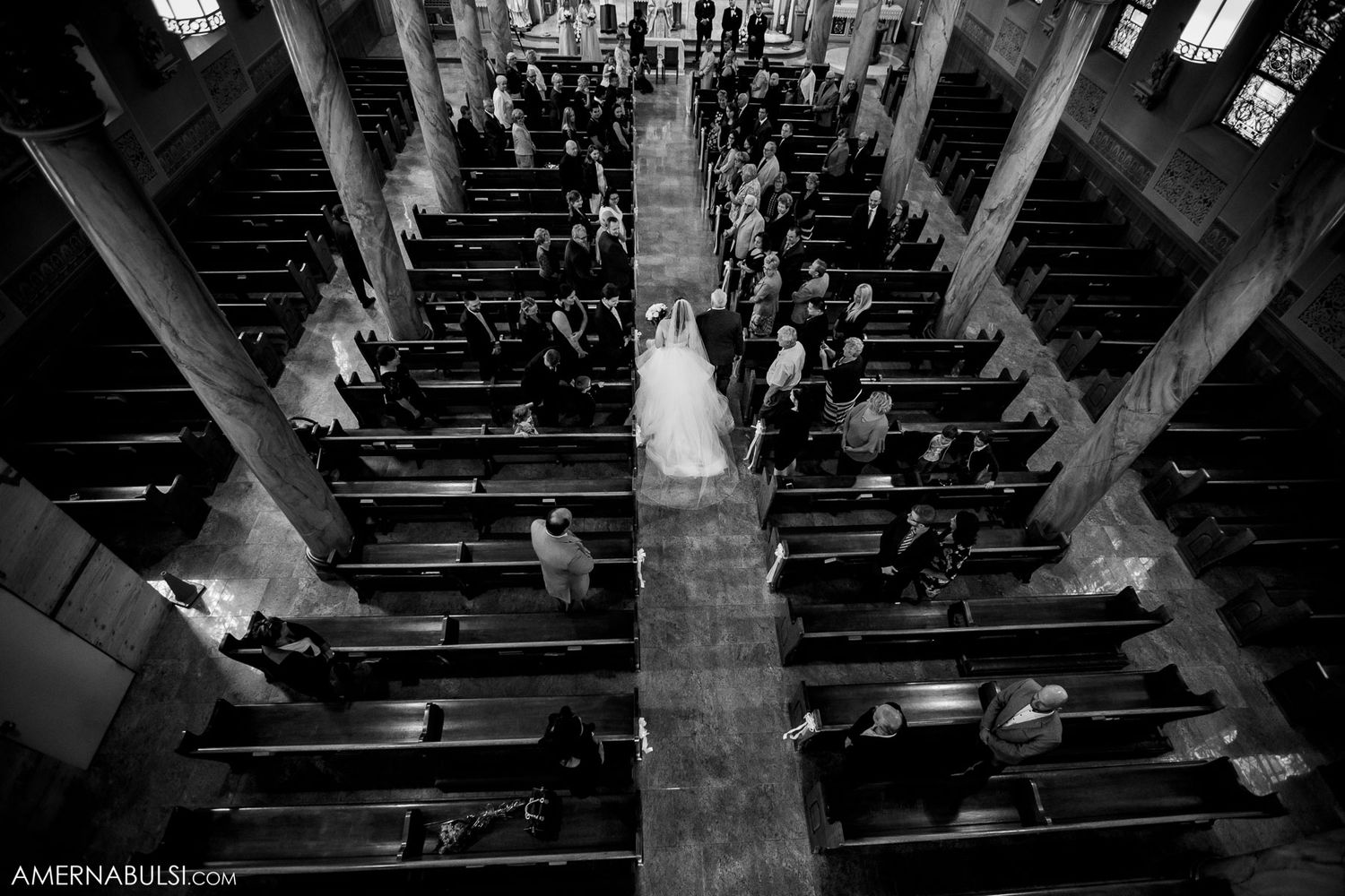 Interior view of a church with wooden pews and dramatic black and white lighting.