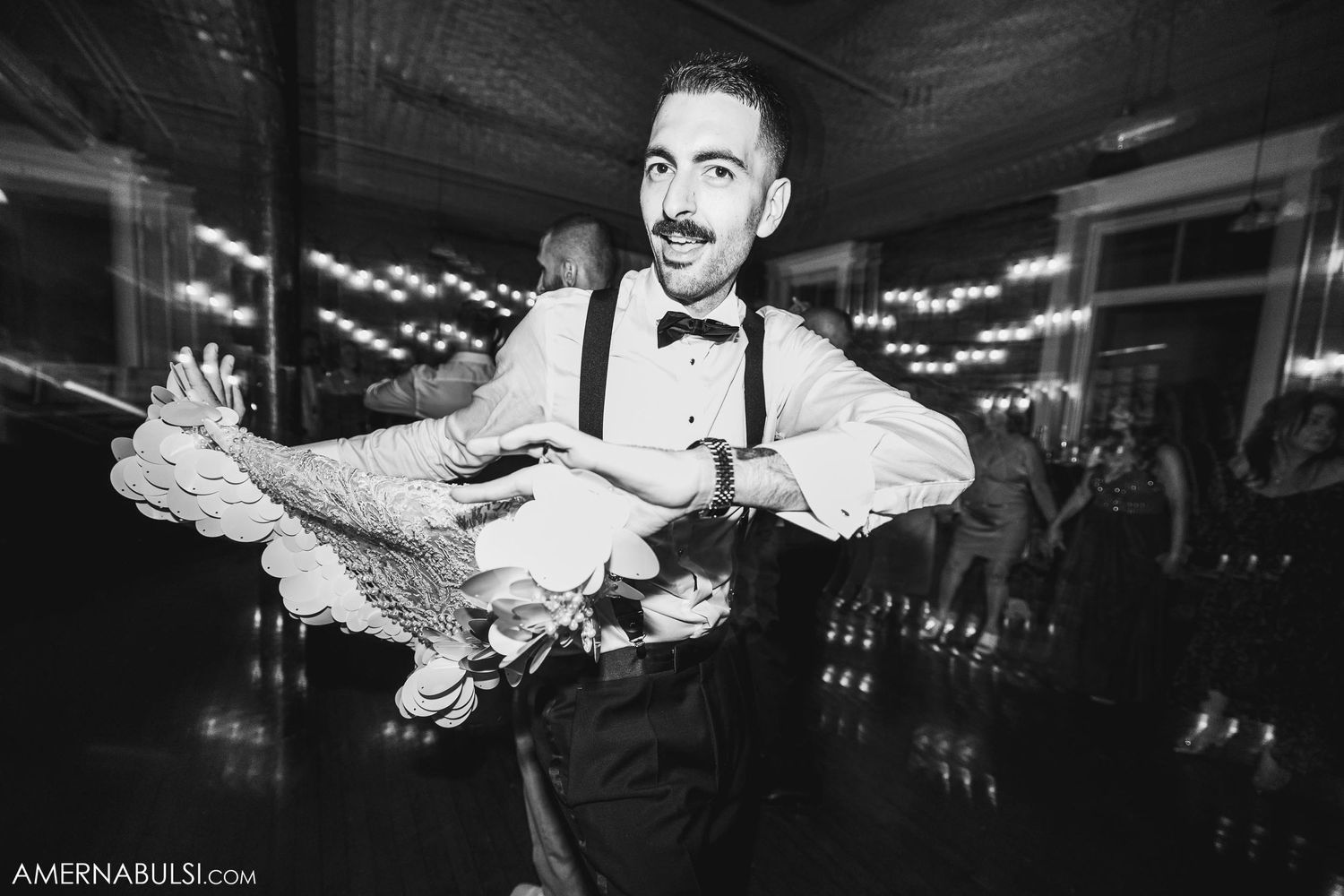Black and white photo of waiter in bowtie carrying food tray with dramatic lighting.