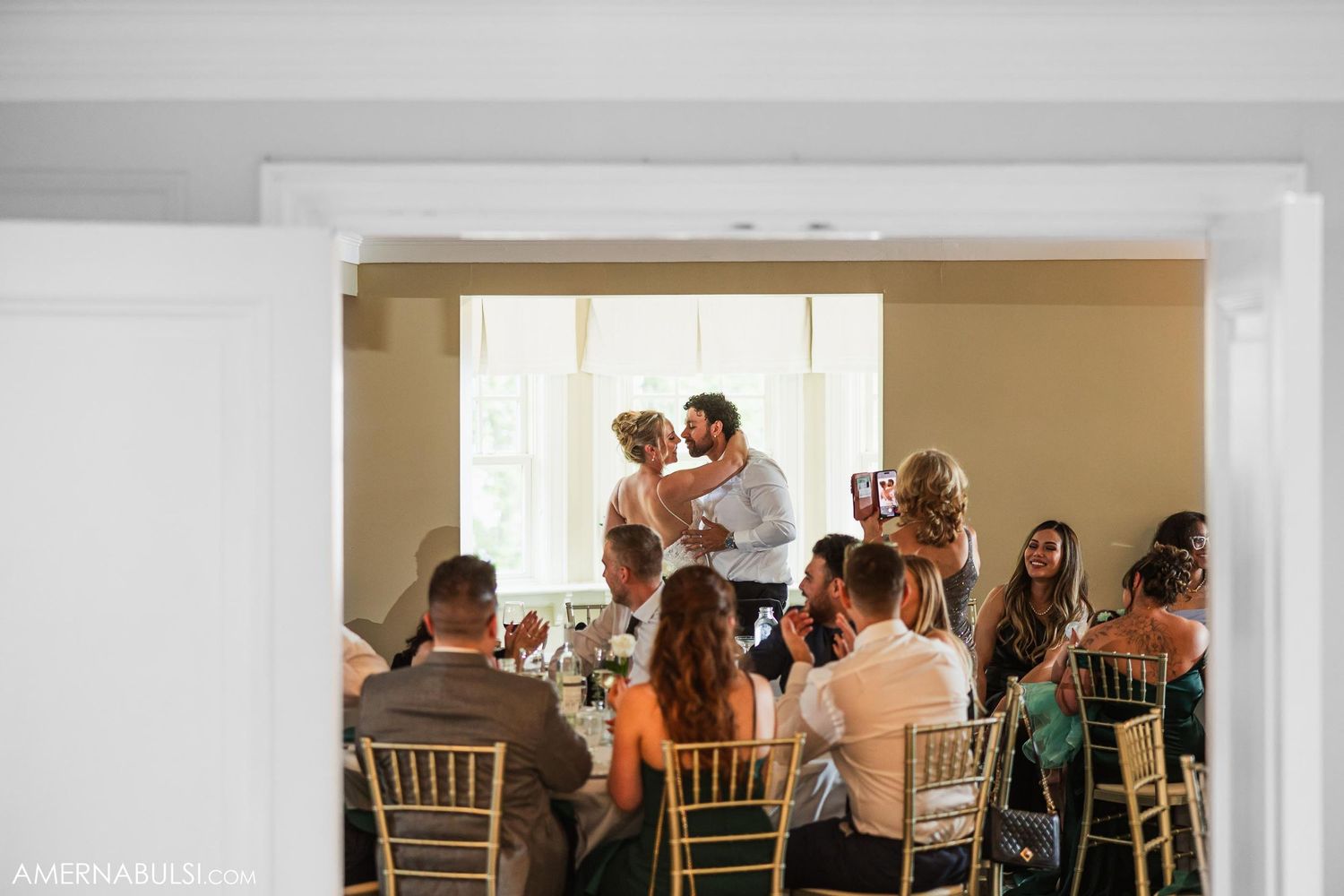 Wedding reception scene showing guests seated at round tables during celebration.