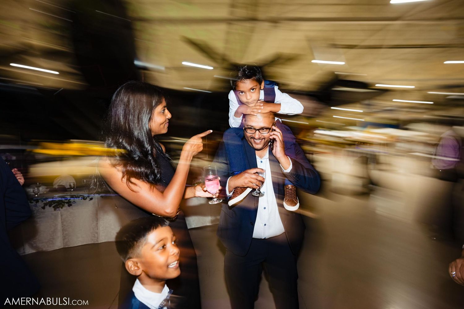 Wedding guests dance and celebrate at a lively reception captured with motion blur effect.