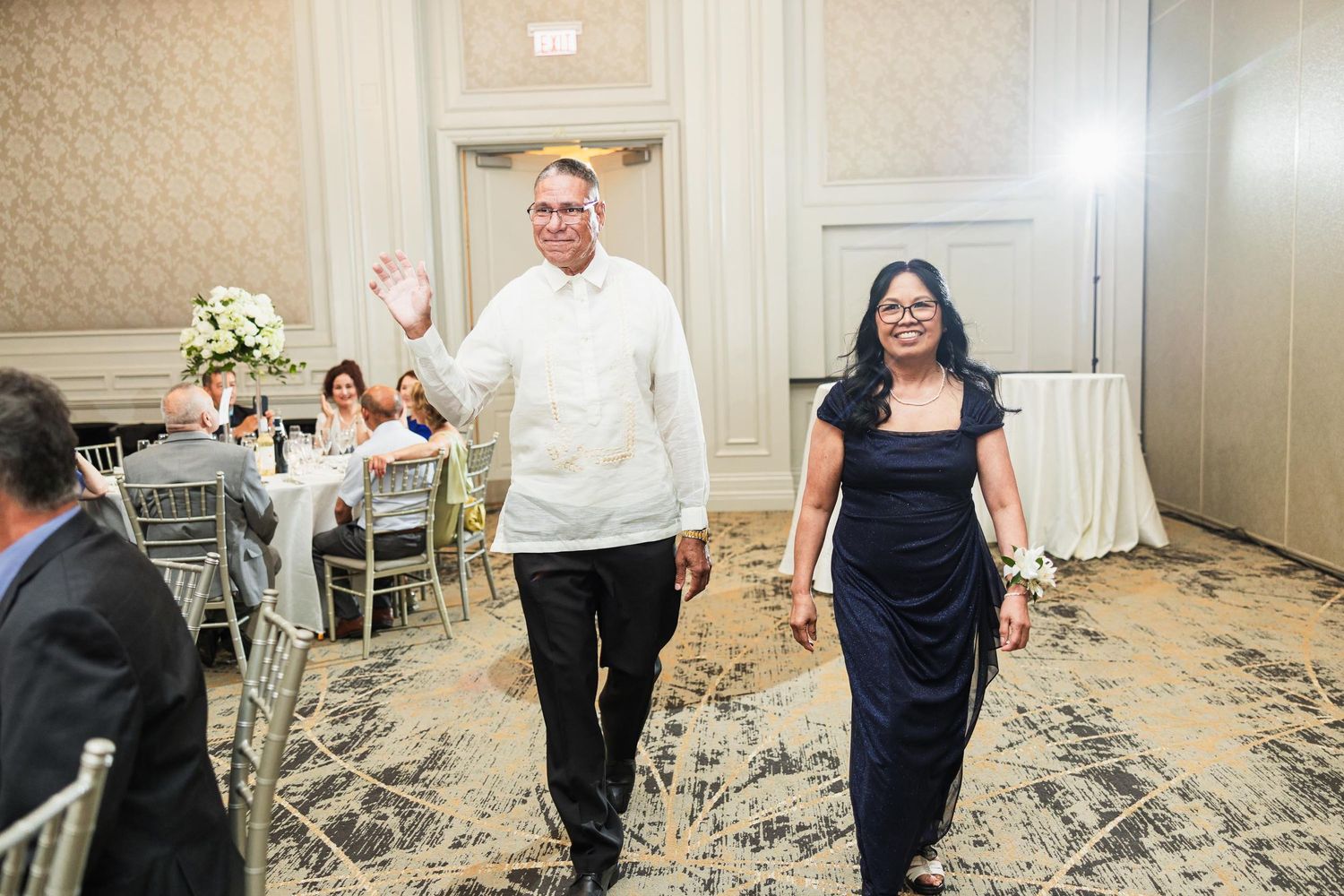 Staff members walk through wedding reception venue with elegant table settings.