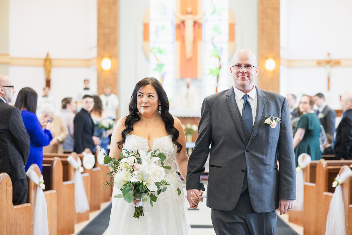 Wedding ceremony in church with bride holding white floral bouquet.