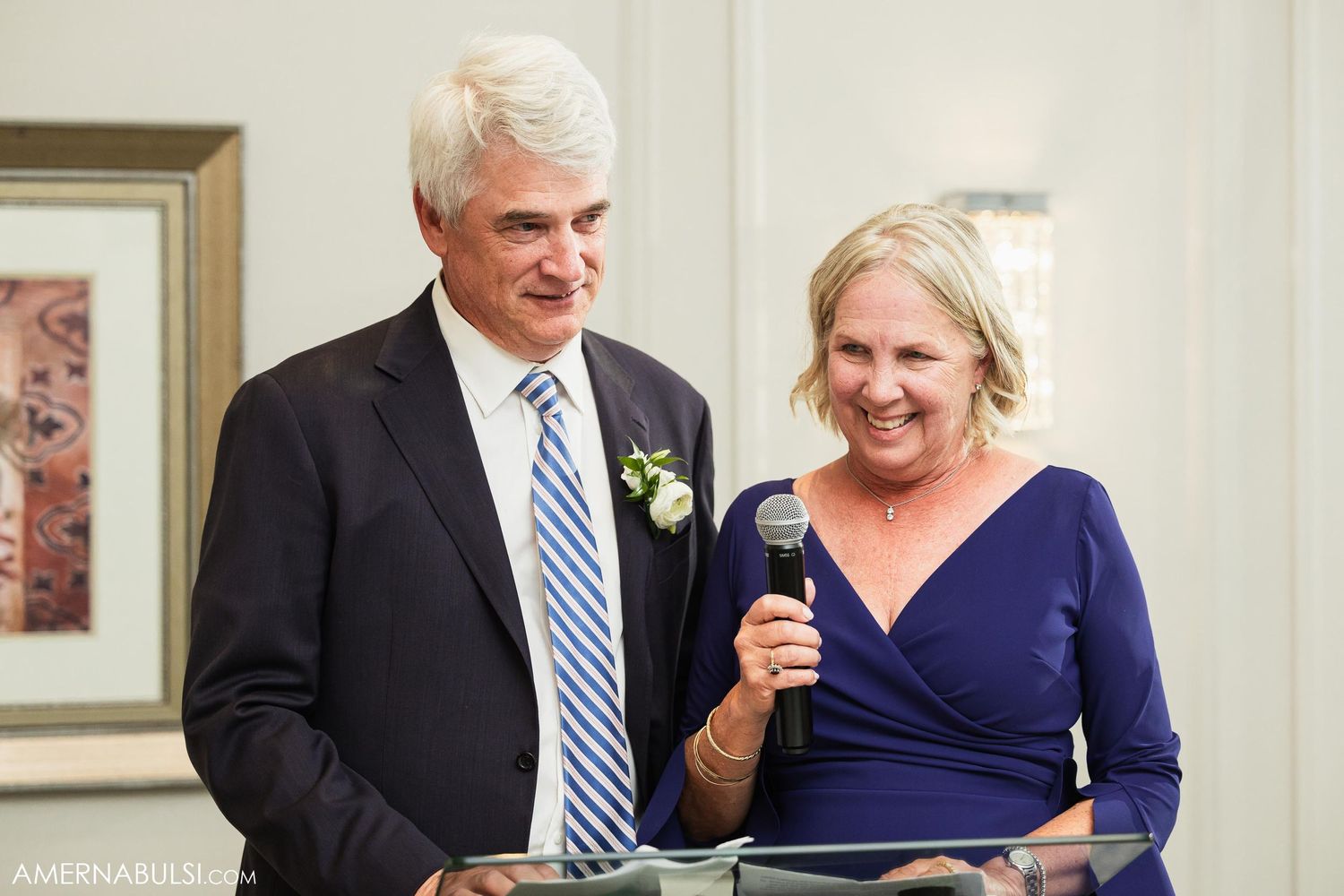 Couple in formal attire delivers wedding speech at elegant reception venue.