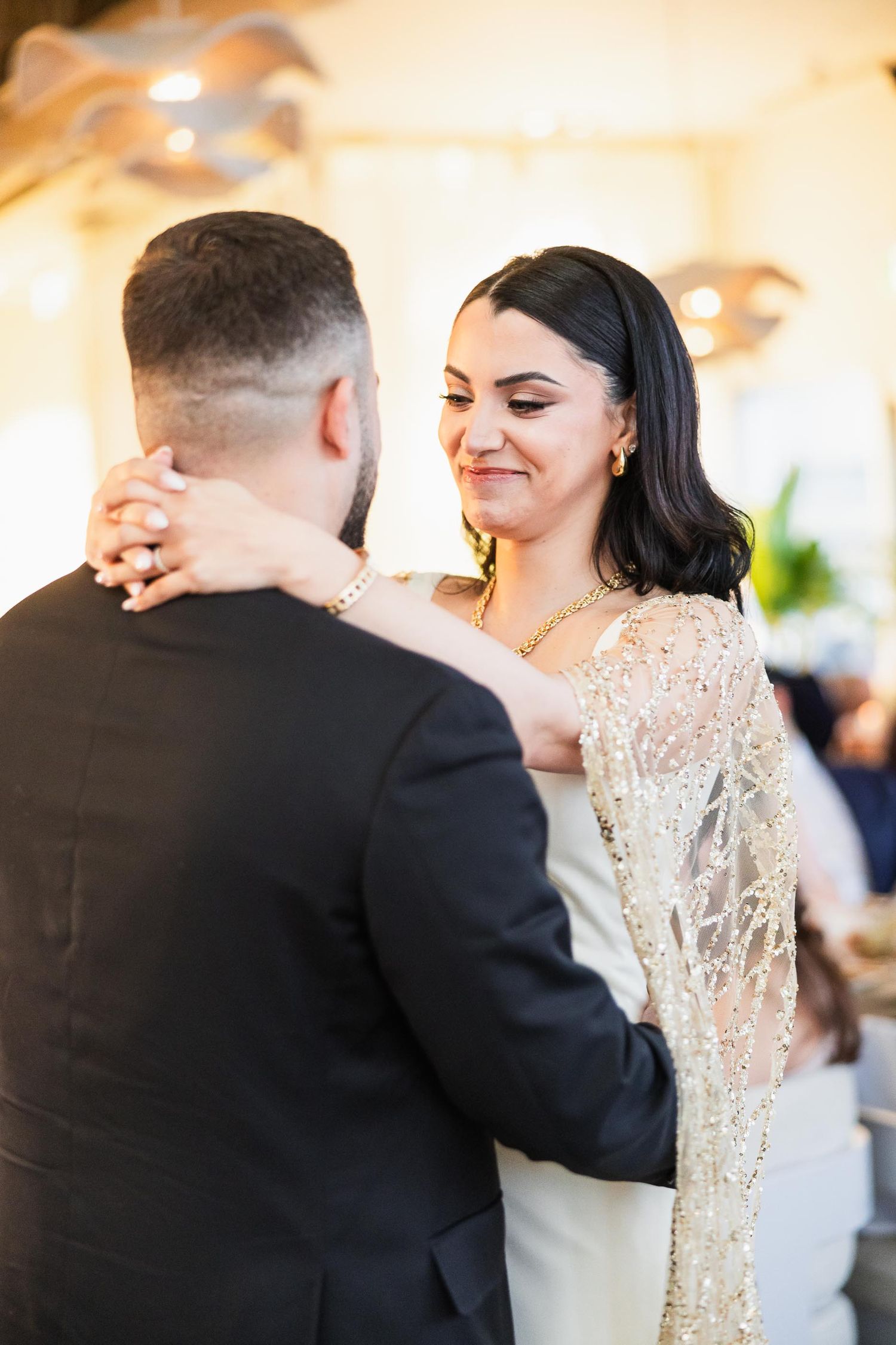A romantic dance moment between newlyweds, with the bride wearing a shimmering gold and white gown.
