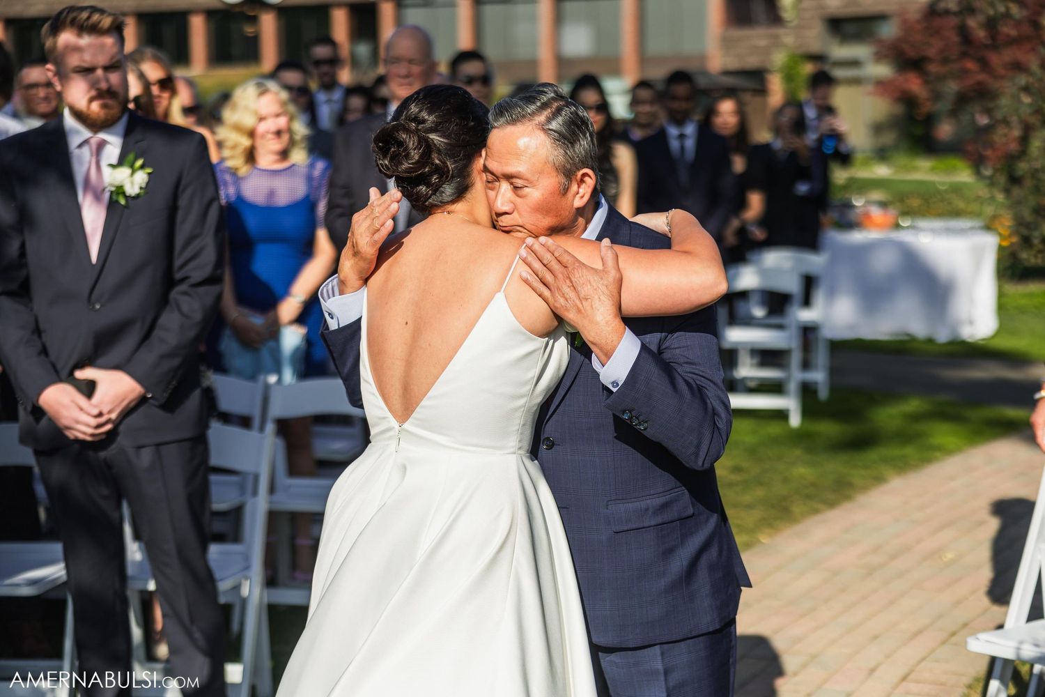 Emotional moment during outdoor wedding ceremony with guests looking on.