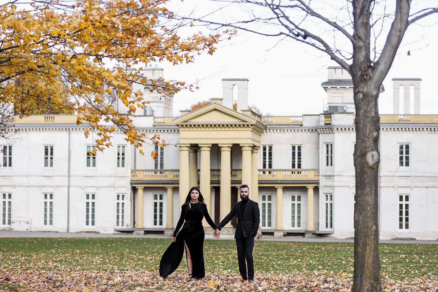 Autumn scene with yellow leaves and classic white colonial architecture in background.