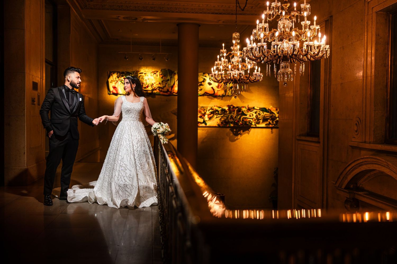 Elegant ballroom wedding reception with ornate chandeliers and romantic lighting.