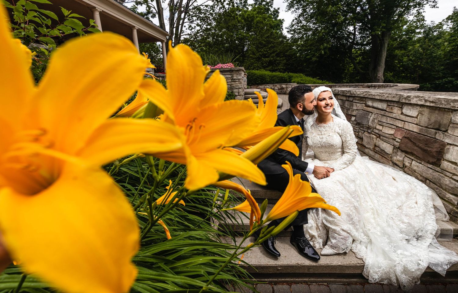 Wedding portraits with vibrant orange daylilies in garden setting.