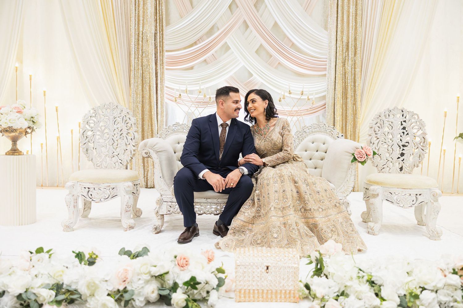 Luxurious white and gold wedding reception setup with ornate decor and floral arrangements.
