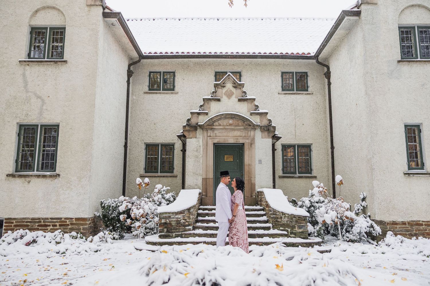 Snow-covered white mansion with traditional architecture and arched windows.