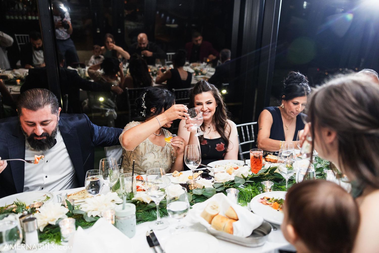 Candid reception dinner scene with guests enjoying conversation and laughter.