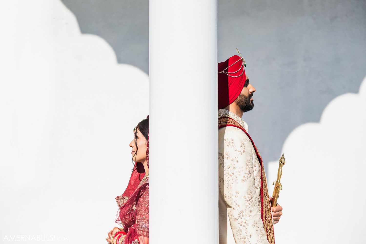 Artistic wedding photo with couple framed by white architectural columns.