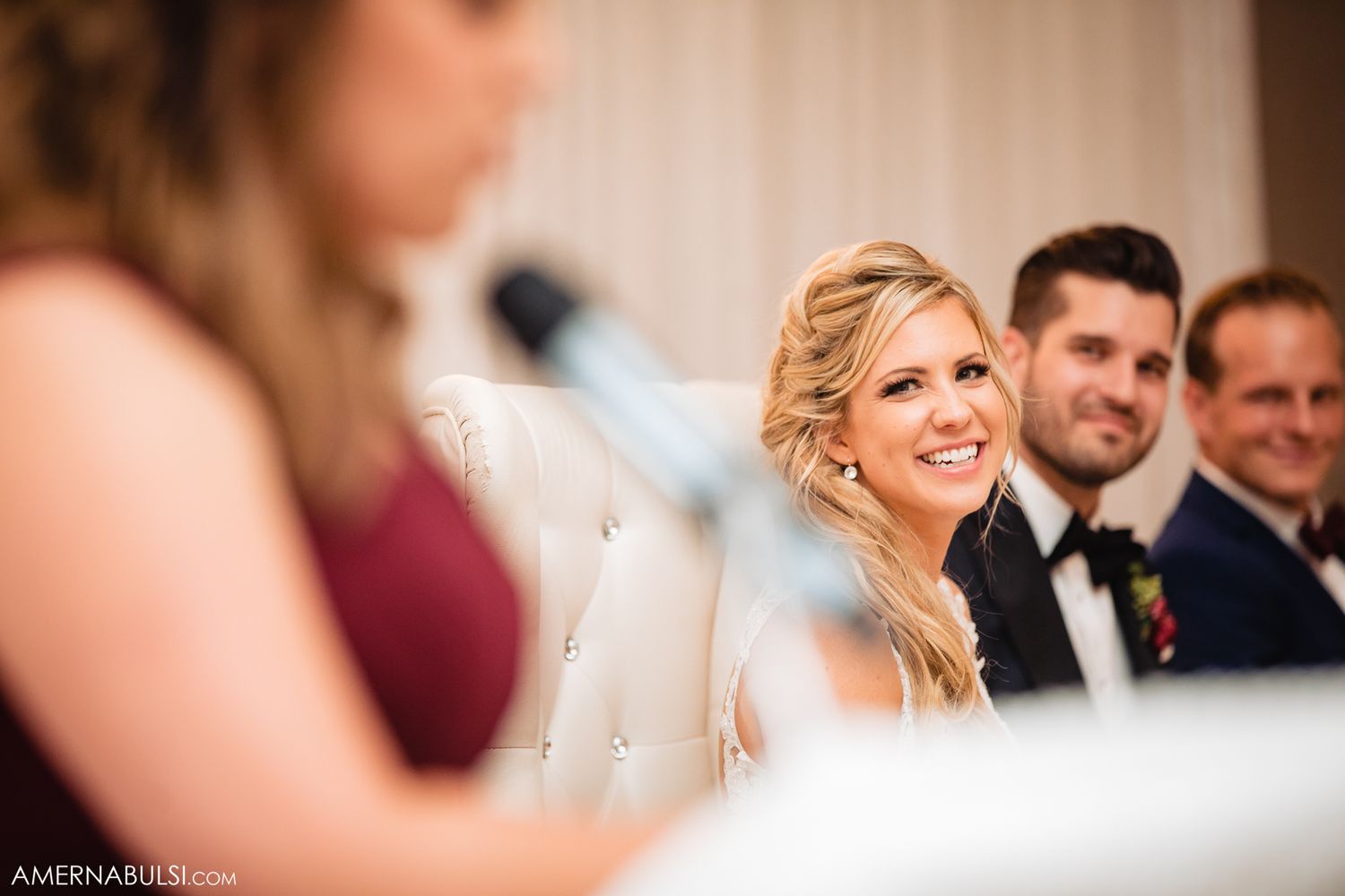 Wedding guests react with joy and laughter during a celebratory moment at an indoor reception.
