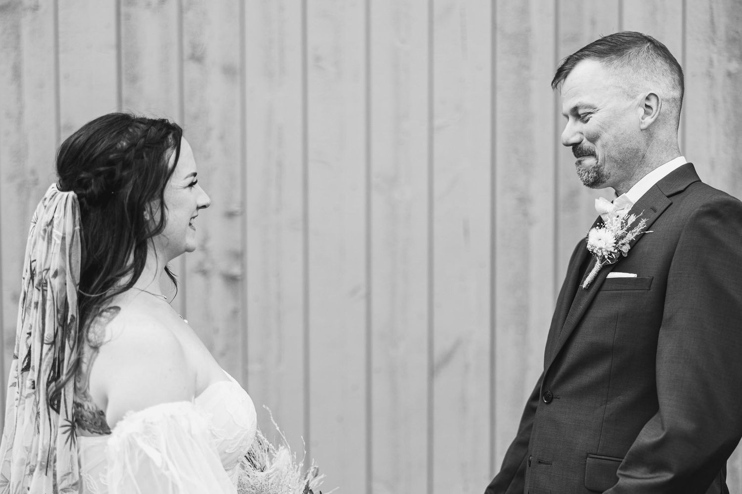 Black and white candid moment of couple laughing during wedding portraits.