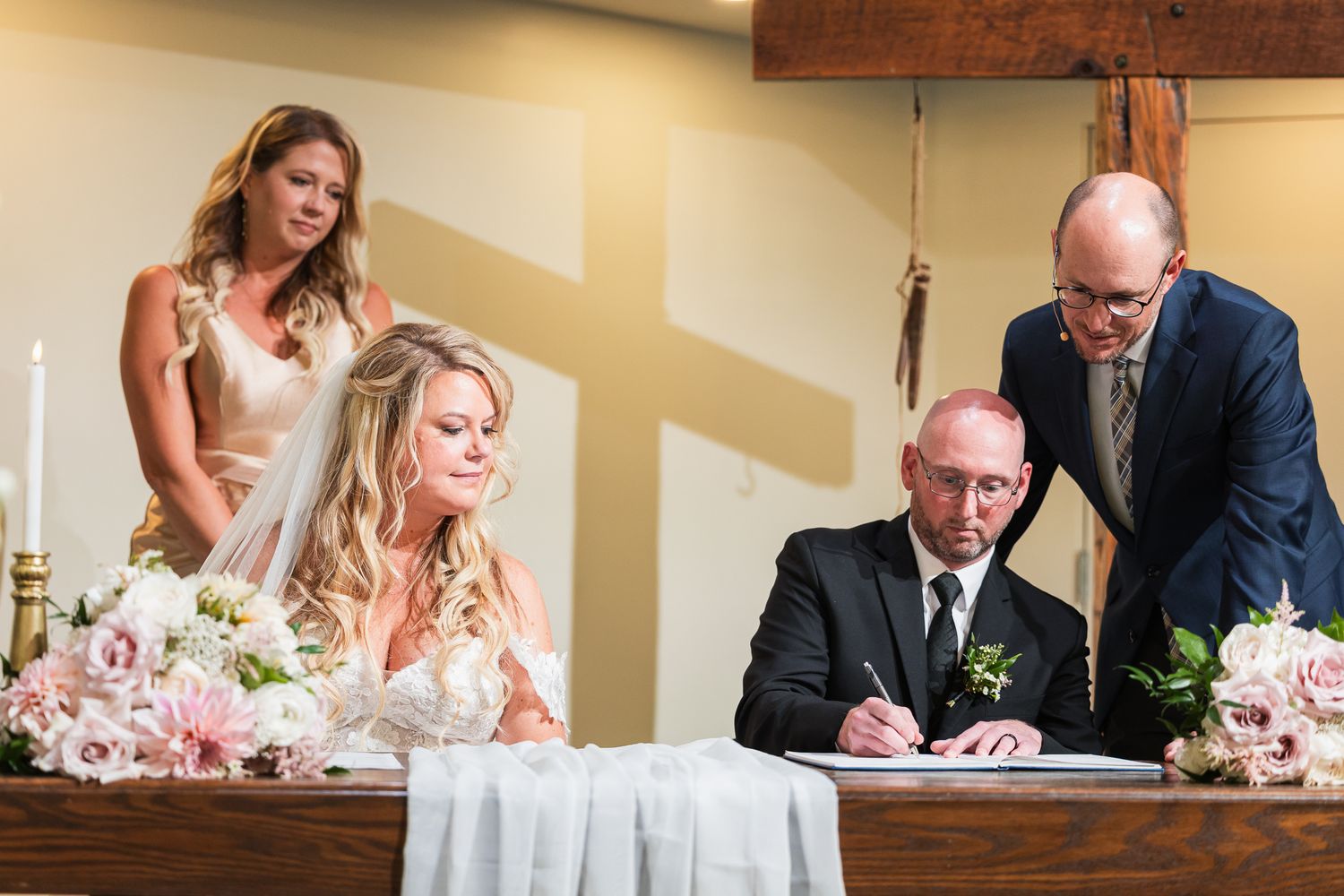 Wedding ceremony signing moment captured in an intimate indoor setting with floral decor.