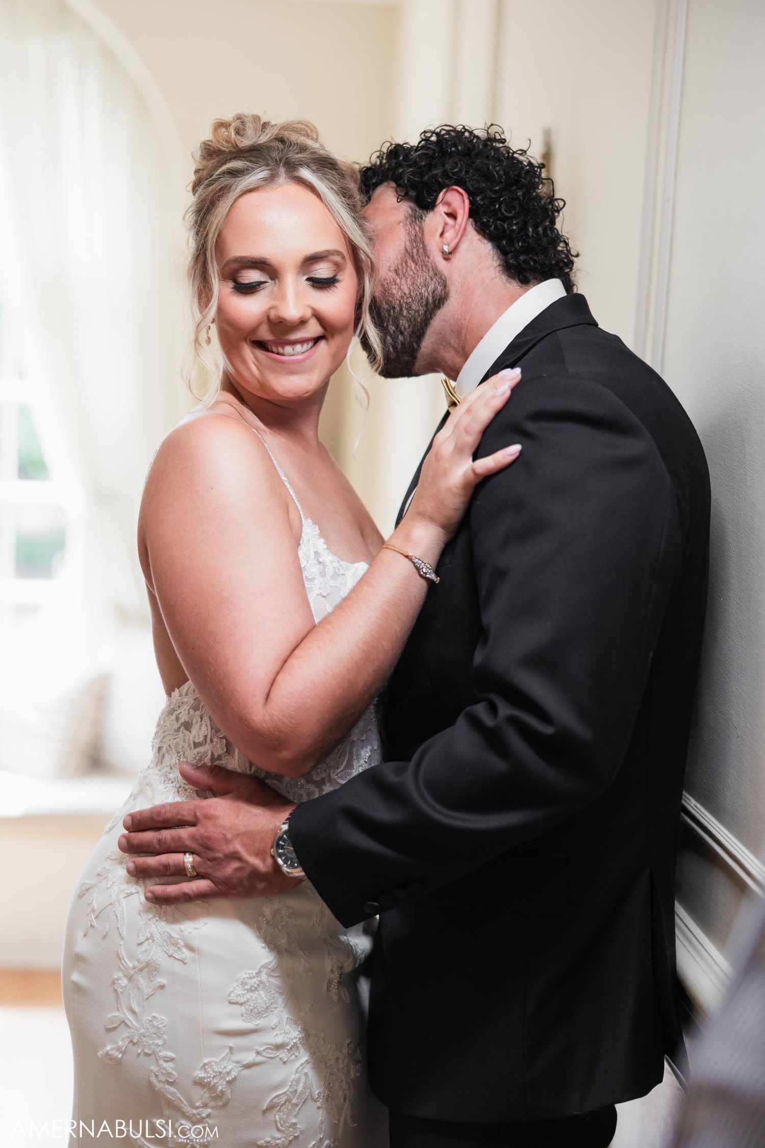 An intimate moment captured between a couple against a white interior wall.