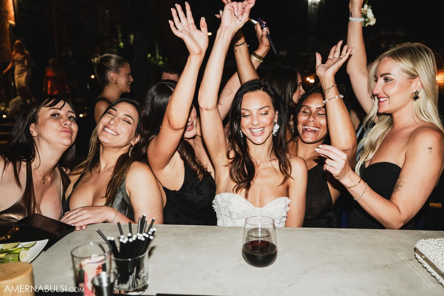 Candid celebration moment with raised hands at reception dinner table.