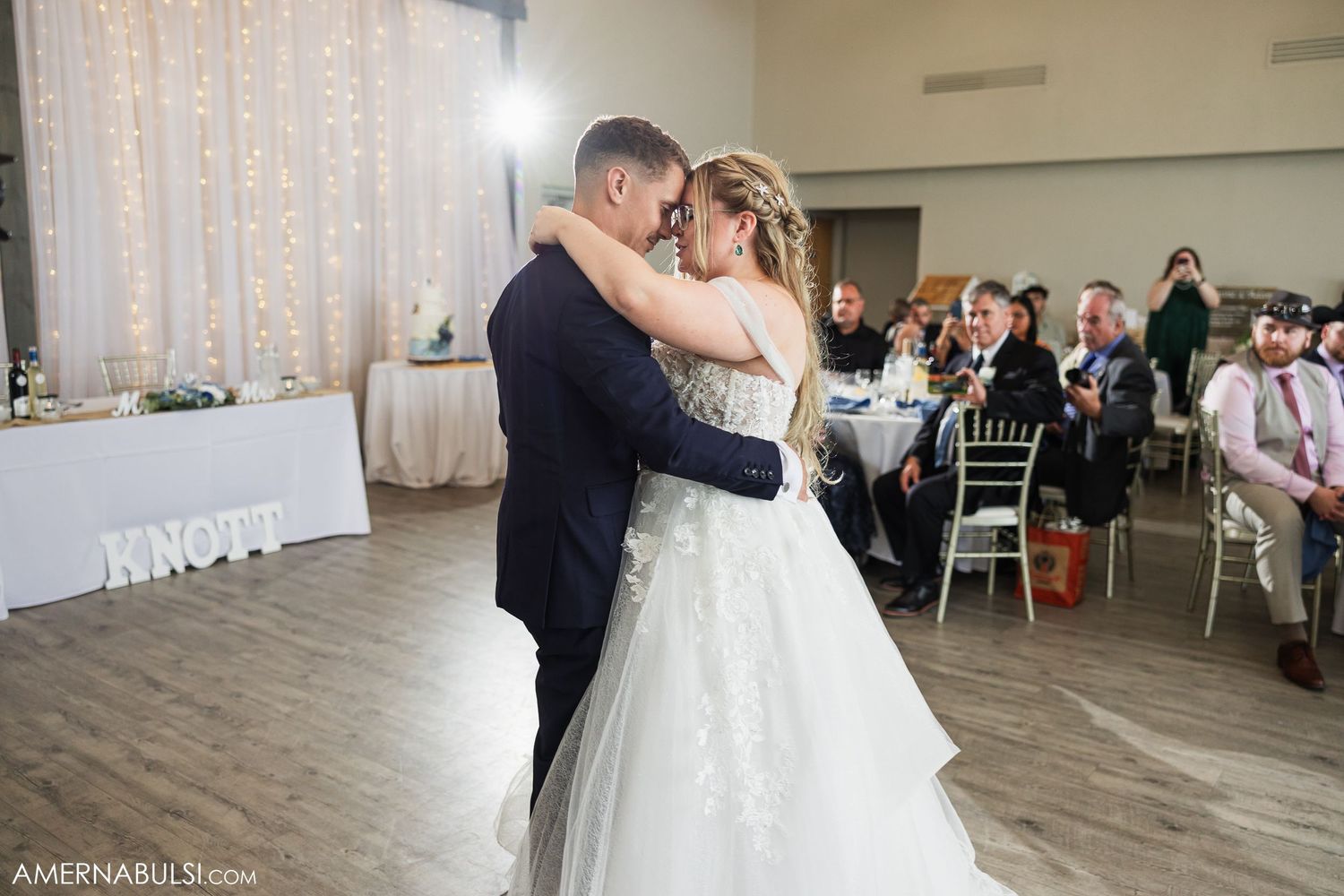 Wedding couple shares their first dance in a beautiful reception hall surrounded by guests.