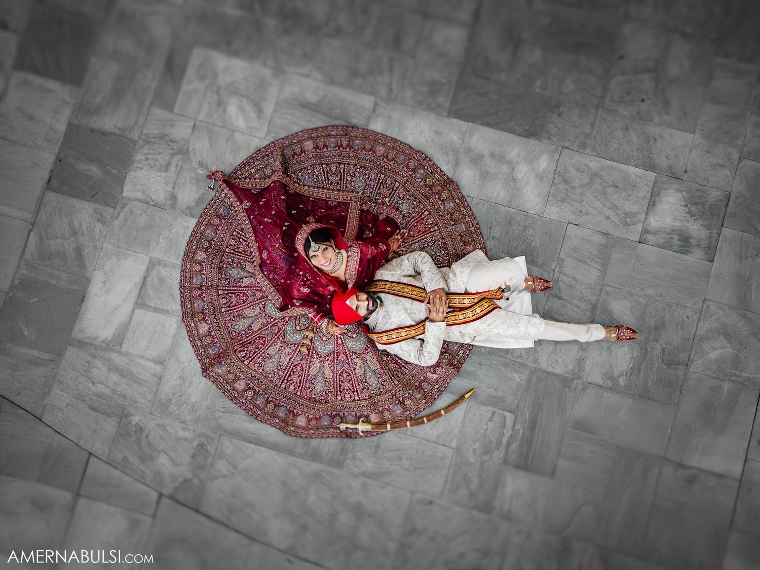 Overhead view of couple in traditional Indian wedding attire creating circular pattern on floor.