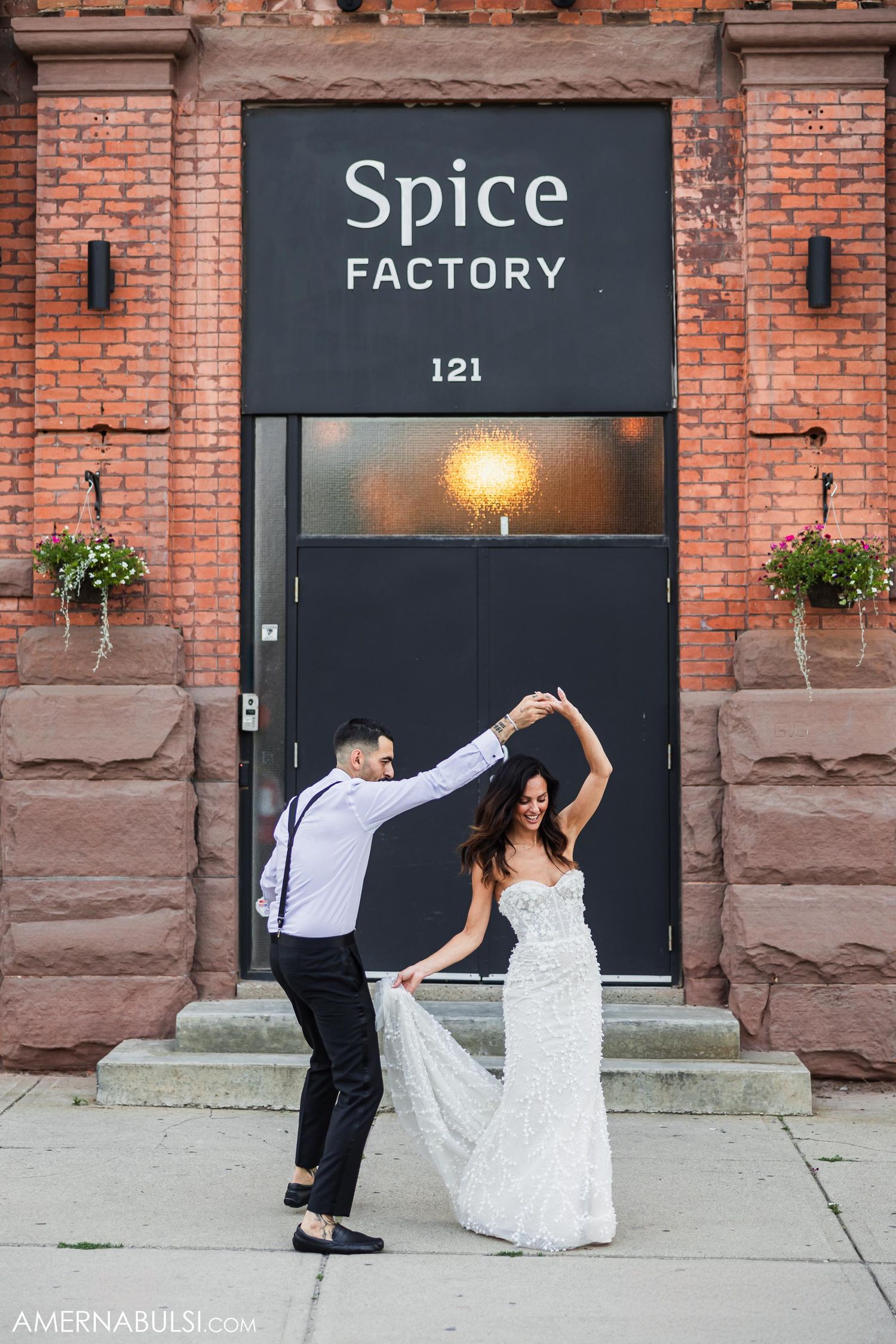 Dancing couple twirls in front of Spice Factory brick building entrance with vintage signage.