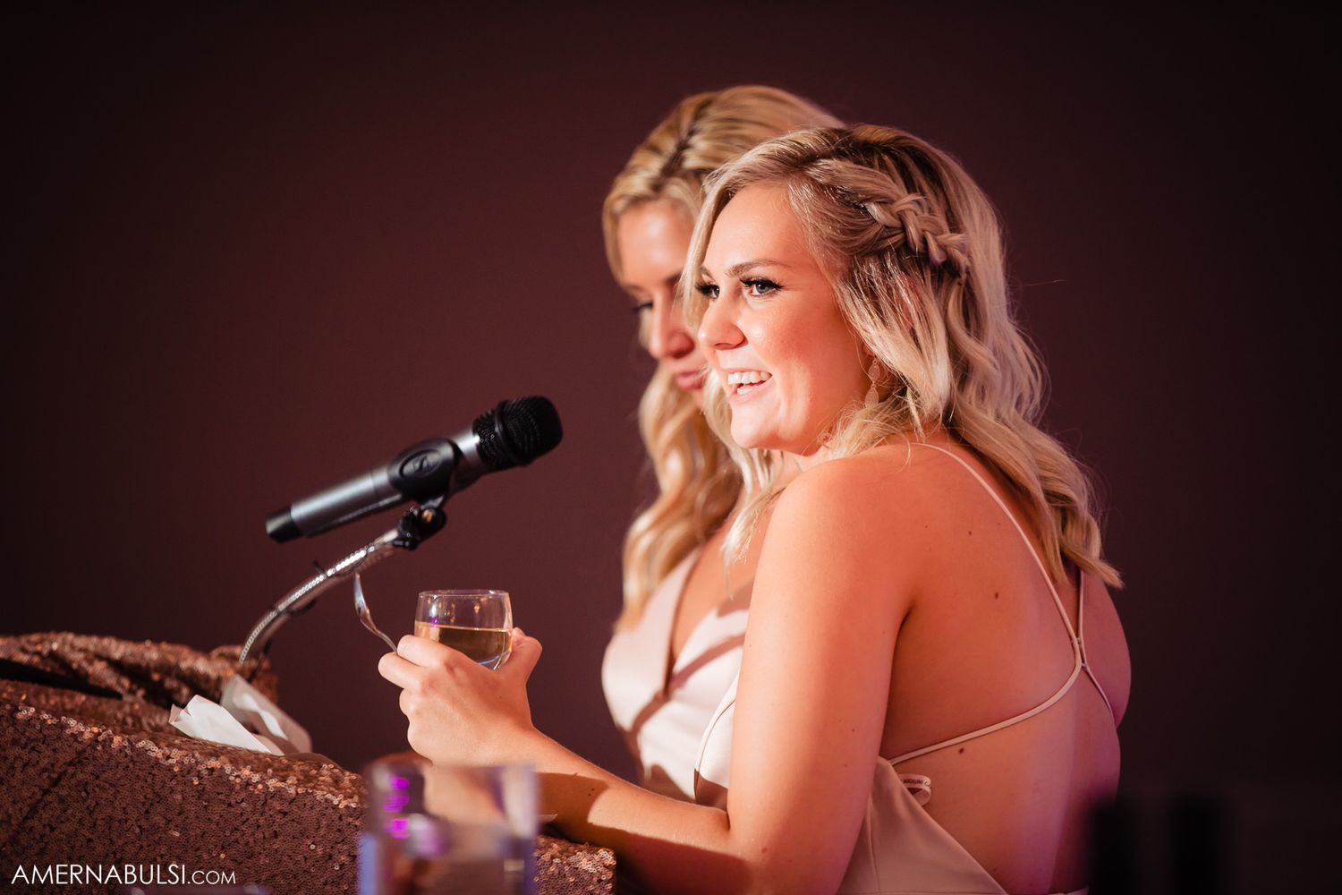Wedding reception performers singing and entertaining guests with microphones on stage in dramatic lighting.