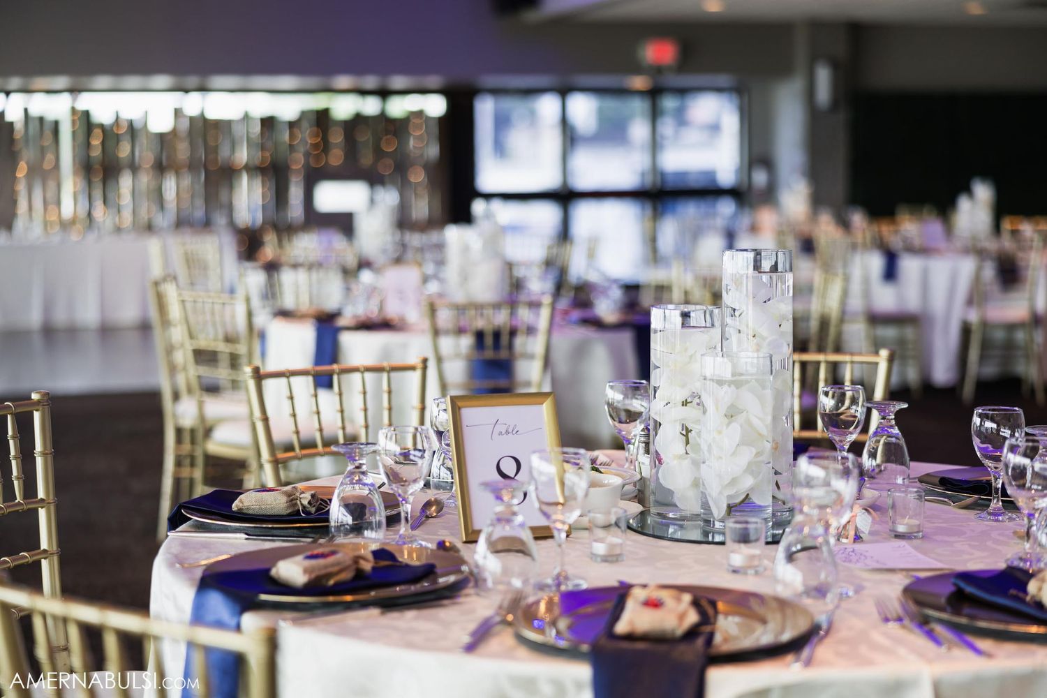 Elegant wedding reception table setting with purple accents and gold chiavari chairs.