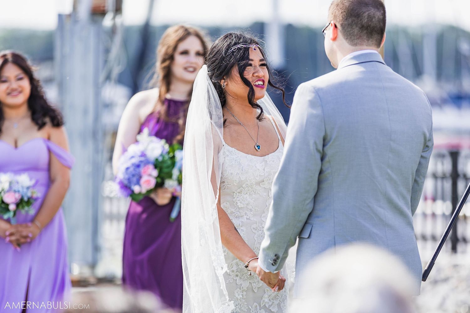 Wedding ceremony by marina with bridesmaids in purple dresses.