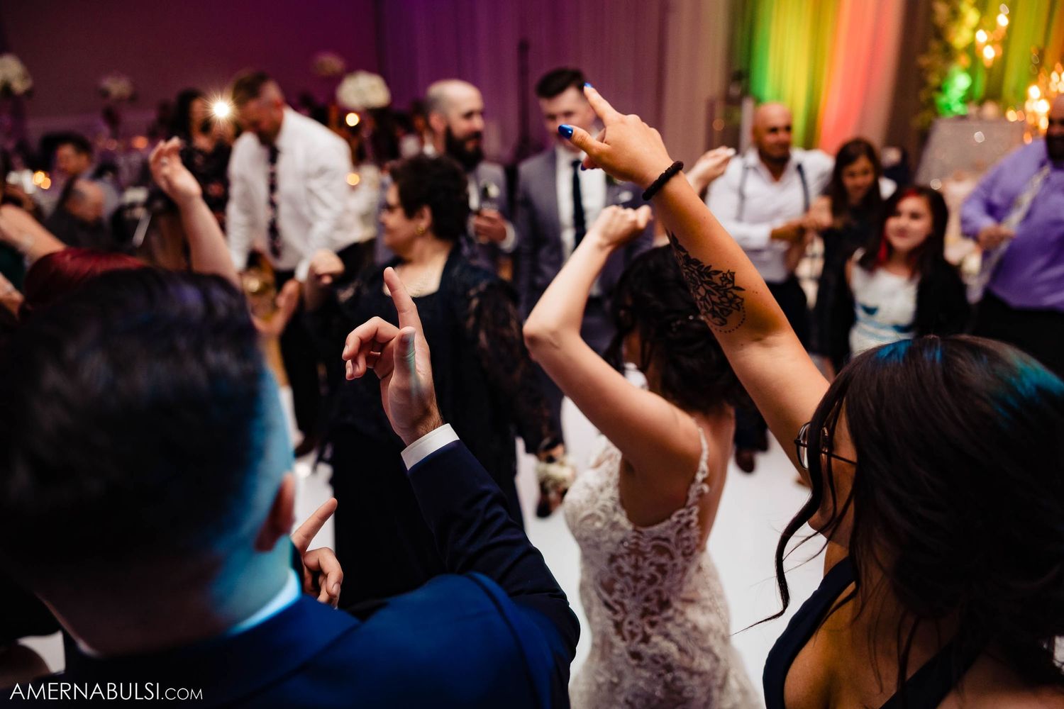 Wedding guests dancing with raised arms during an energetic reception celebration.