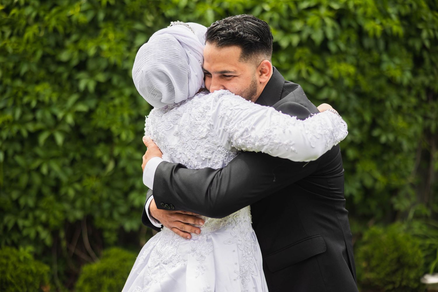 Emotional embrace between newlyweds in garden setting during wedding ceremony.