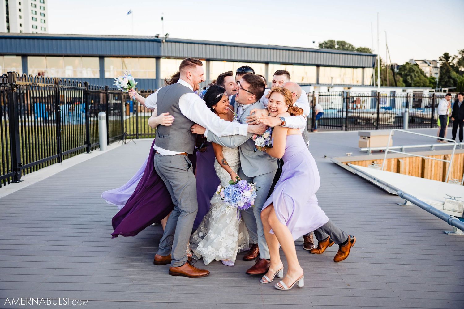 Wedding party sharing a fun group hug moment on outdoor deck.