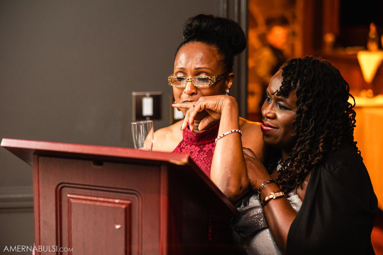 Two wedding guests enjoying drinks and conversation at an evening reception.