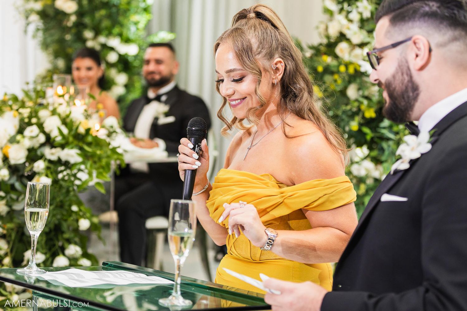 Wedding reception guests in formal attire enjoying champagne at elegantly decorated table.