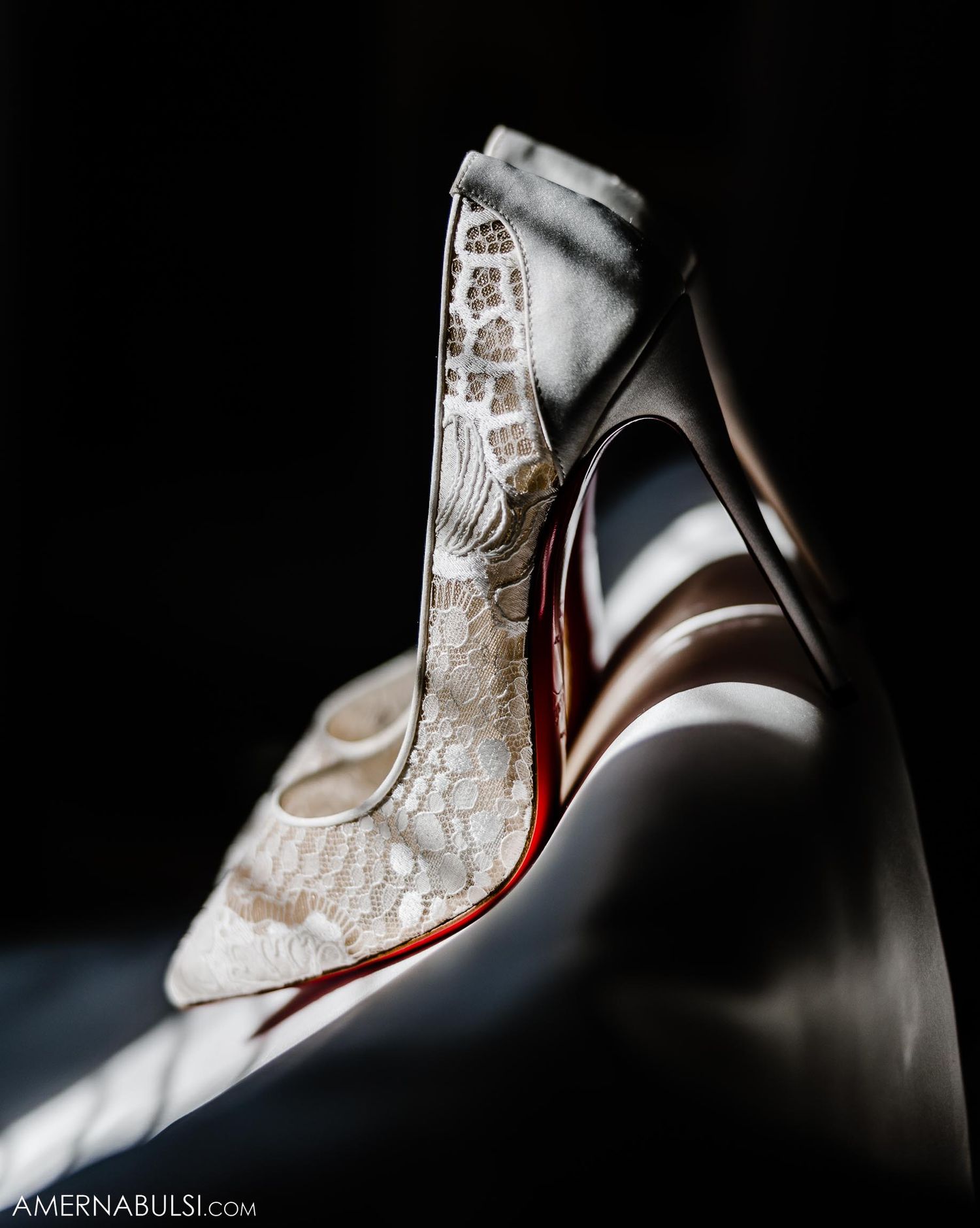 Artistic close-up of lace wedding shoe with dramatic lighting and shadow detail.