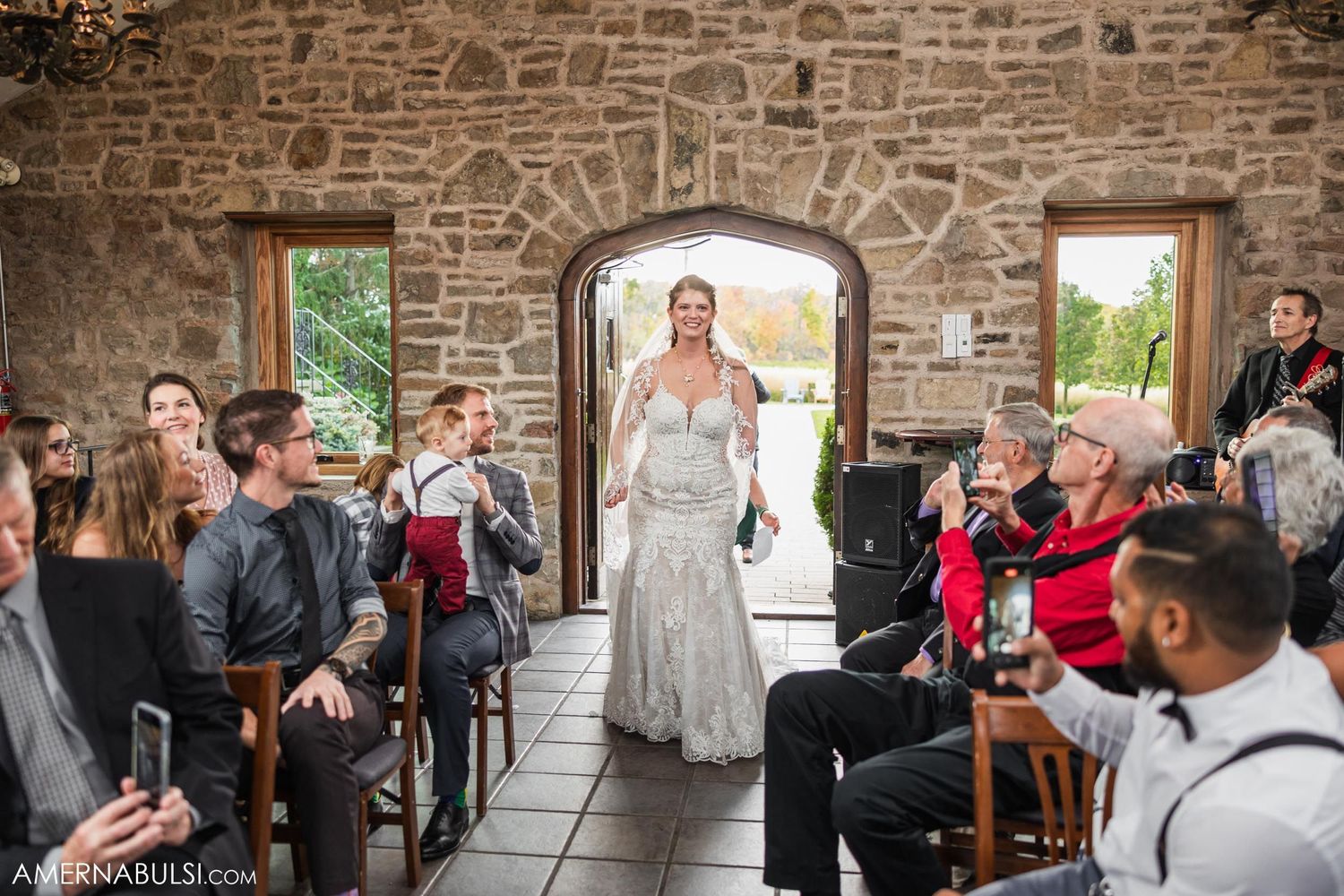 Wedding ceremony in progress inside stone-walled venue with arched doorway.