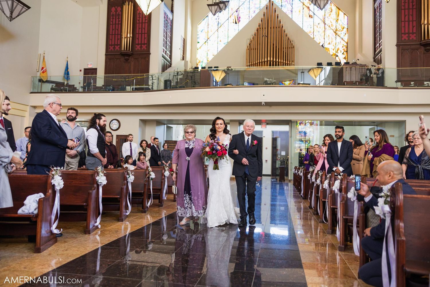 Wedding ceremony in progress inside traditional church with organ loft and wooden pews.