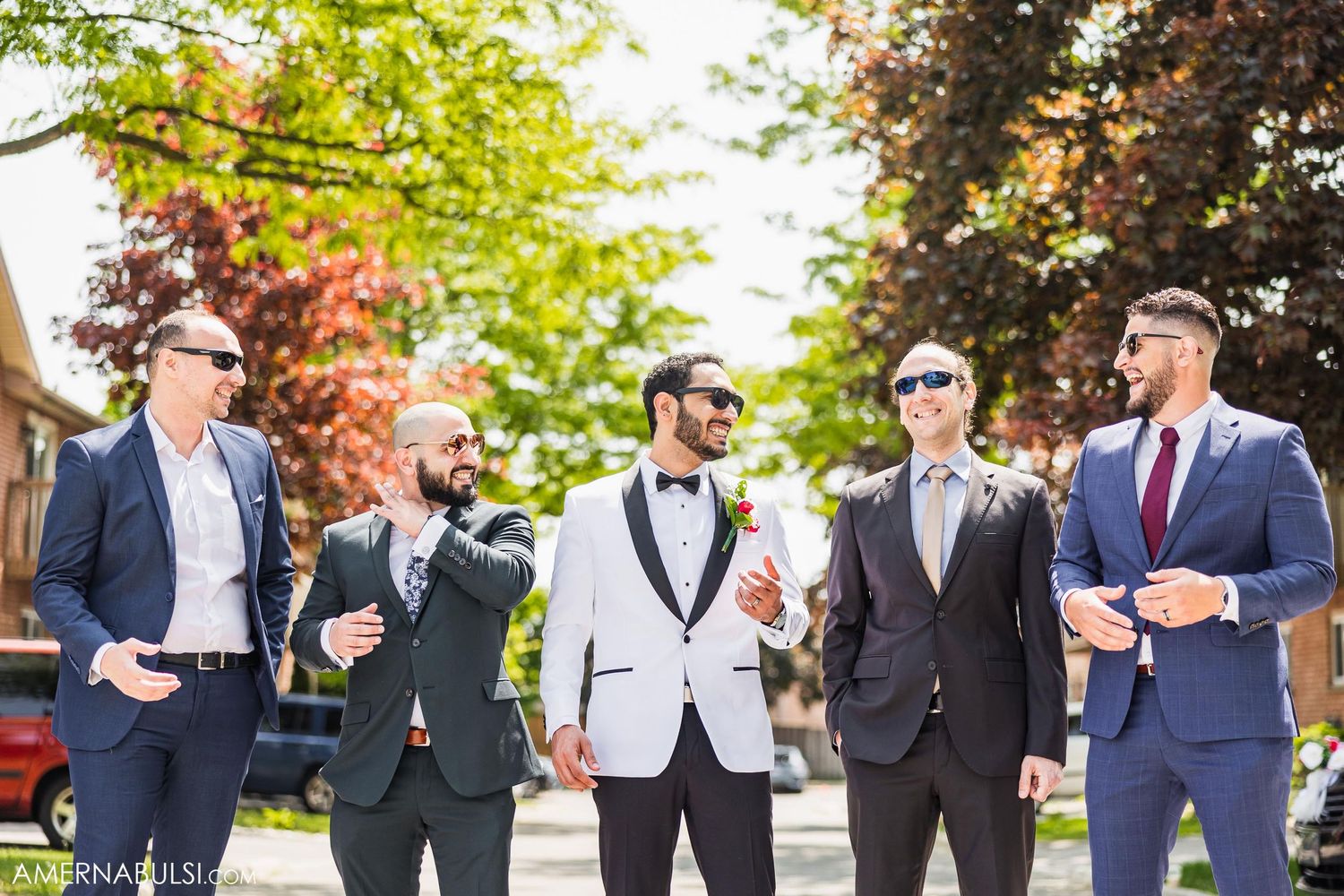 A group of groomsmen in formal attire standing together outdoors.