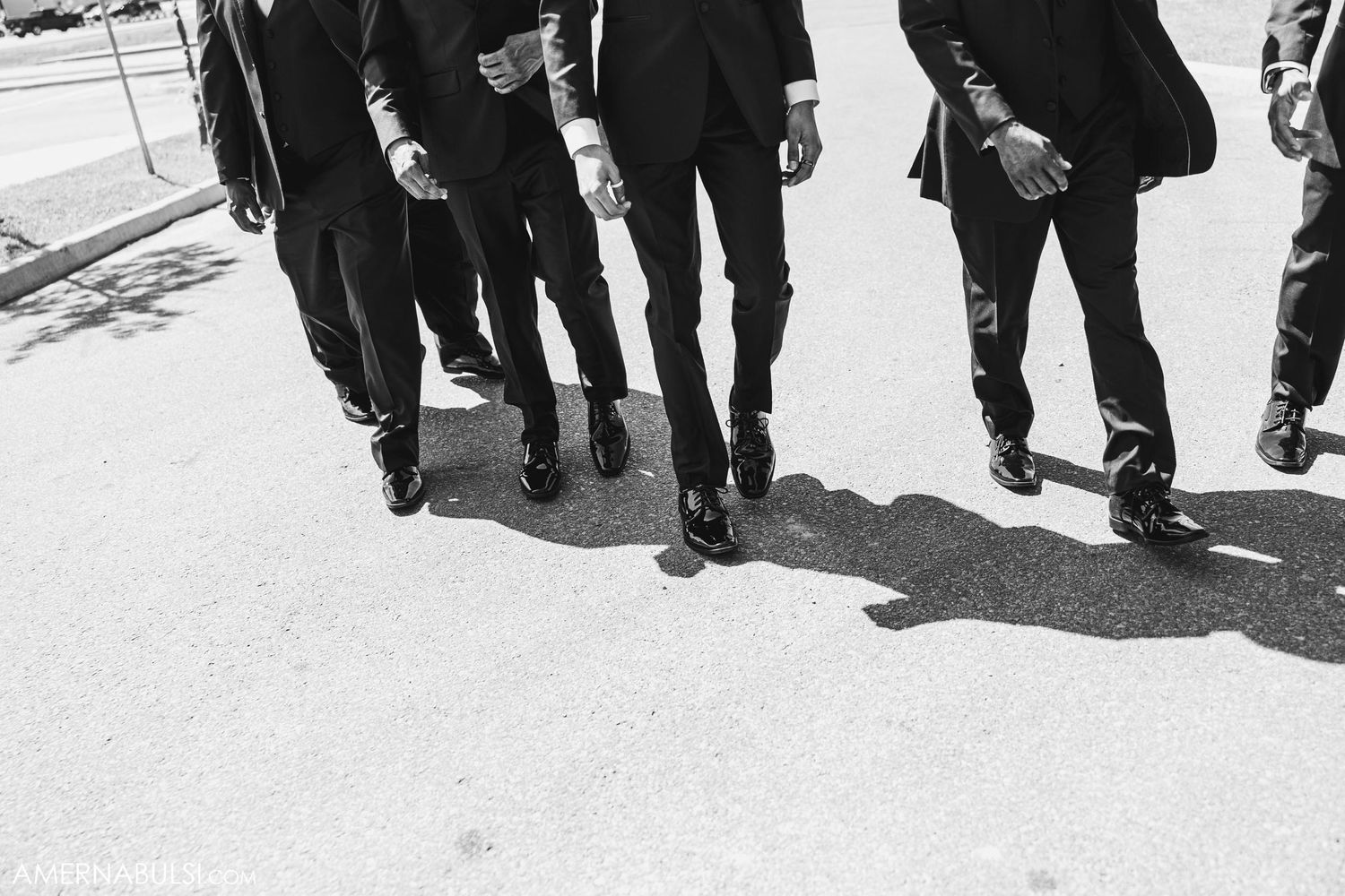 Black and white photo of groomsmen's shoes and legs walking in unison.