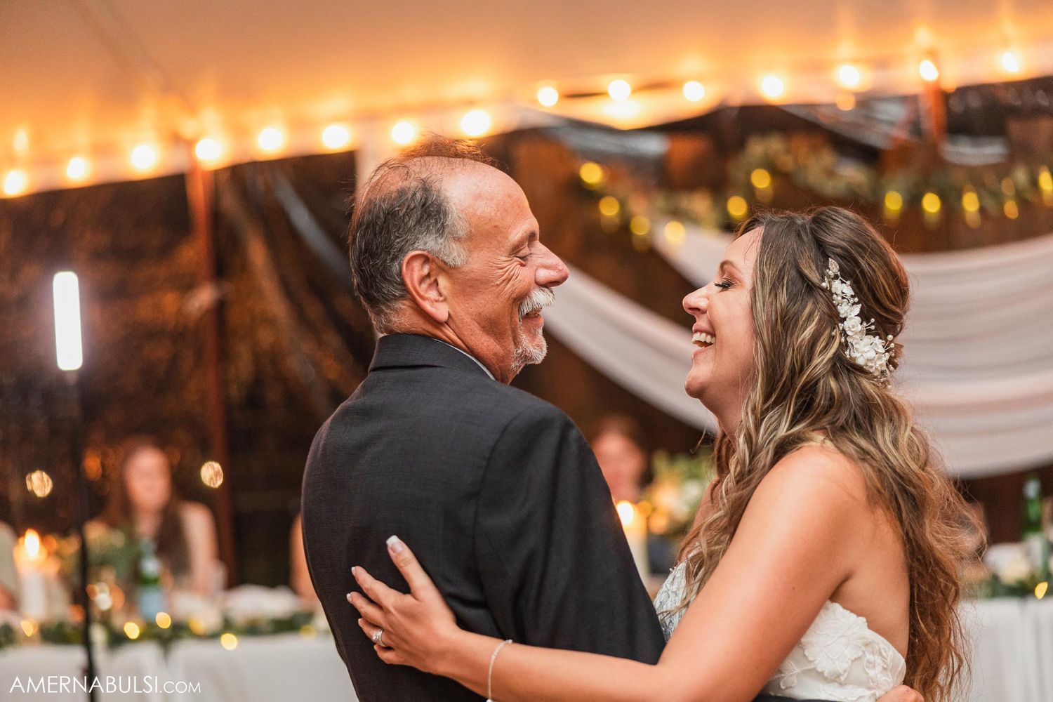 A tender dance moment at a wedding reception with warm string lights glowing in the background.