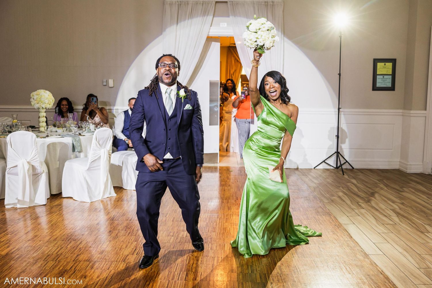 Wedding party members dancing energetically in formal attire during reception celebrations.