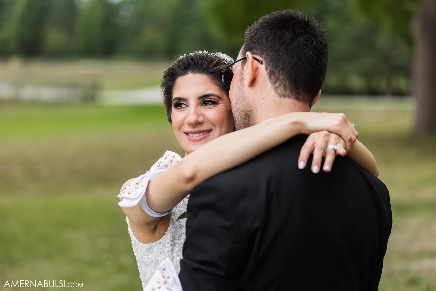 Romantic outdoor wedding portrait with couple embracing in natural setting.