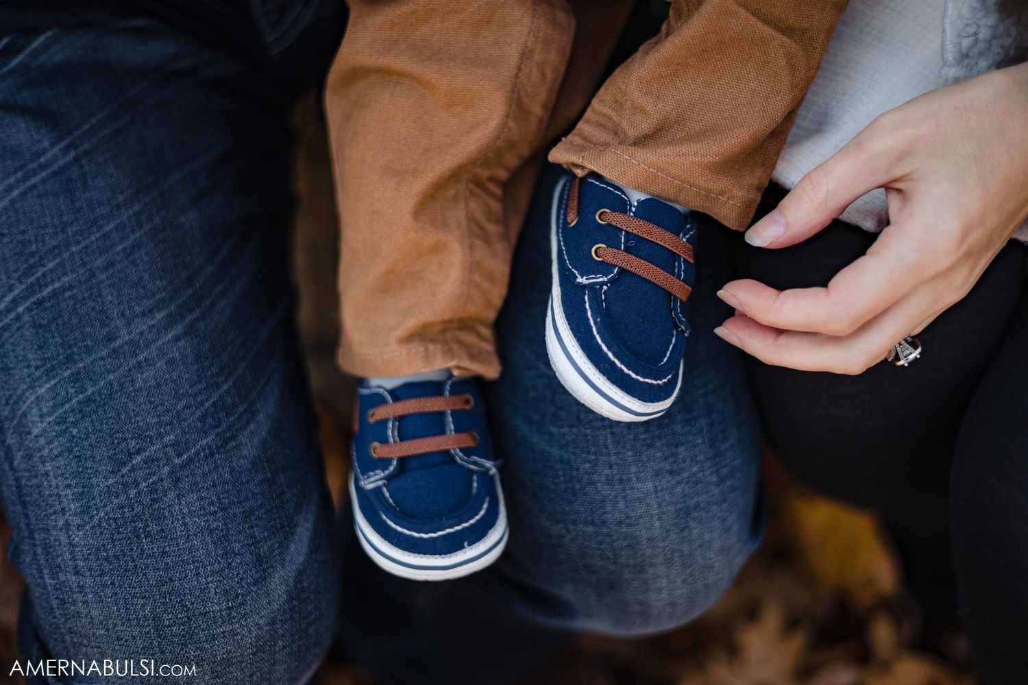 Close-up of tiny navy blue baby shoes with white trim.