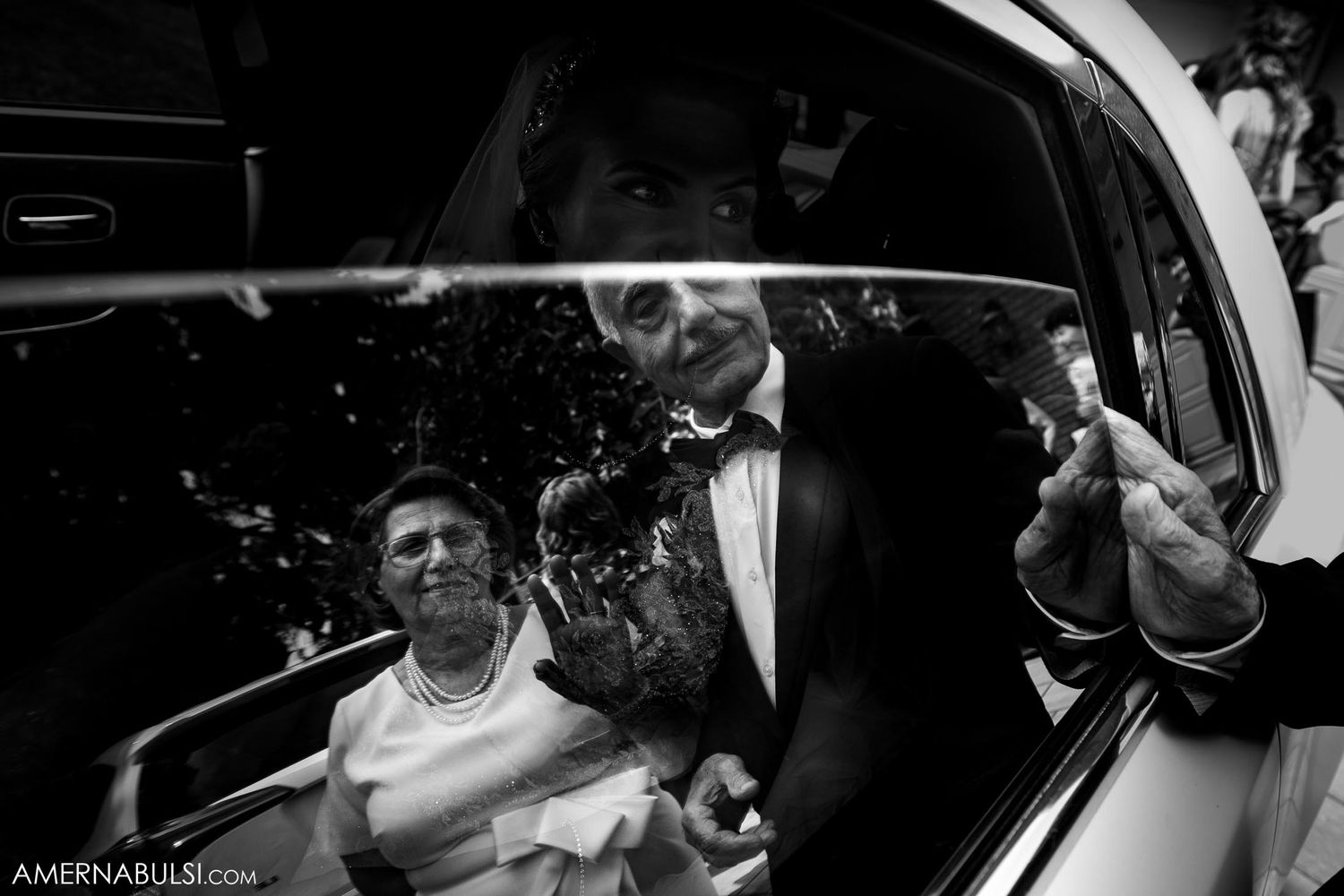Black and white candid photo of celebratory moment in wedding car.