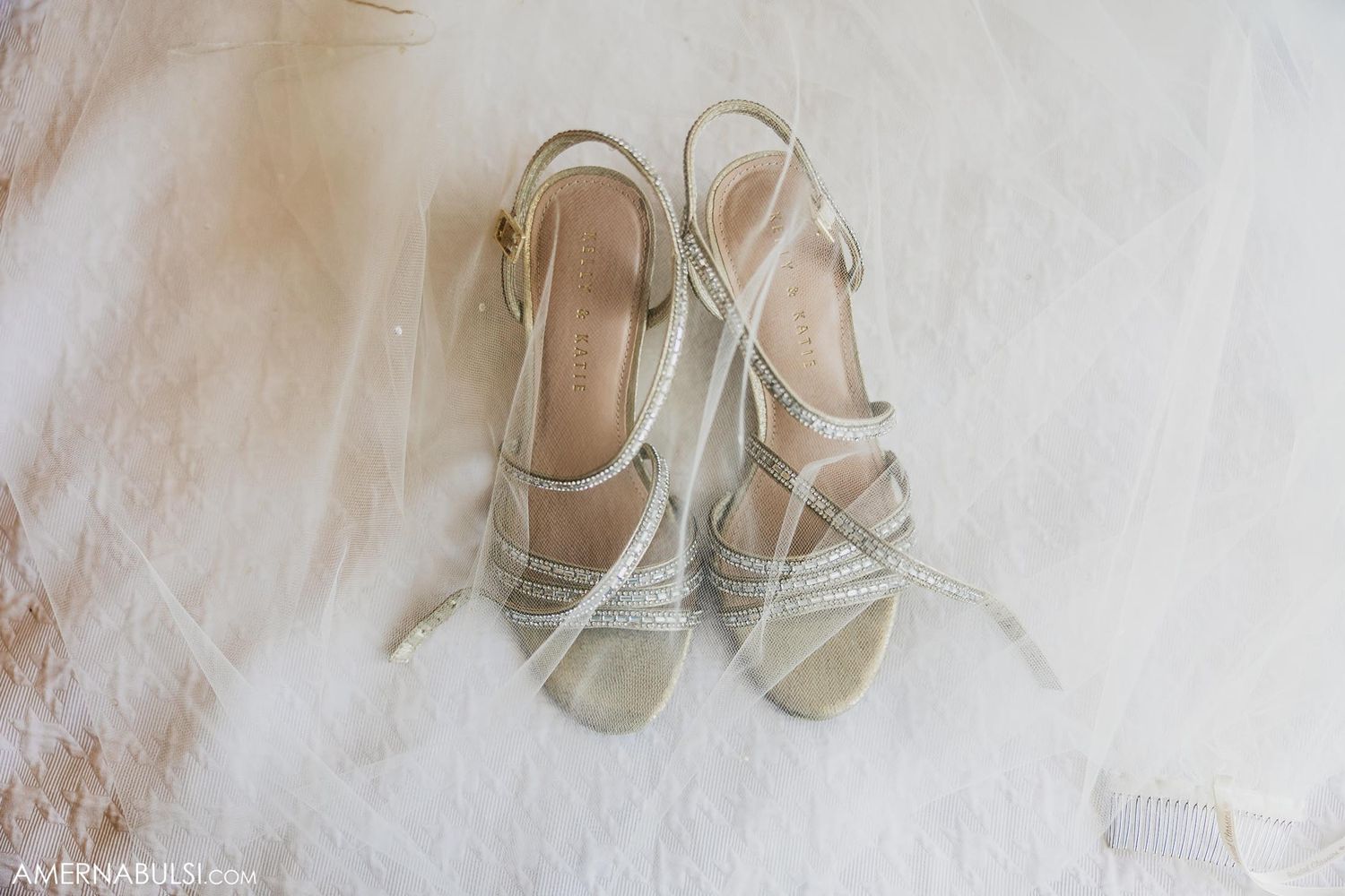 Elegant white strappy wedding sandals on light background.