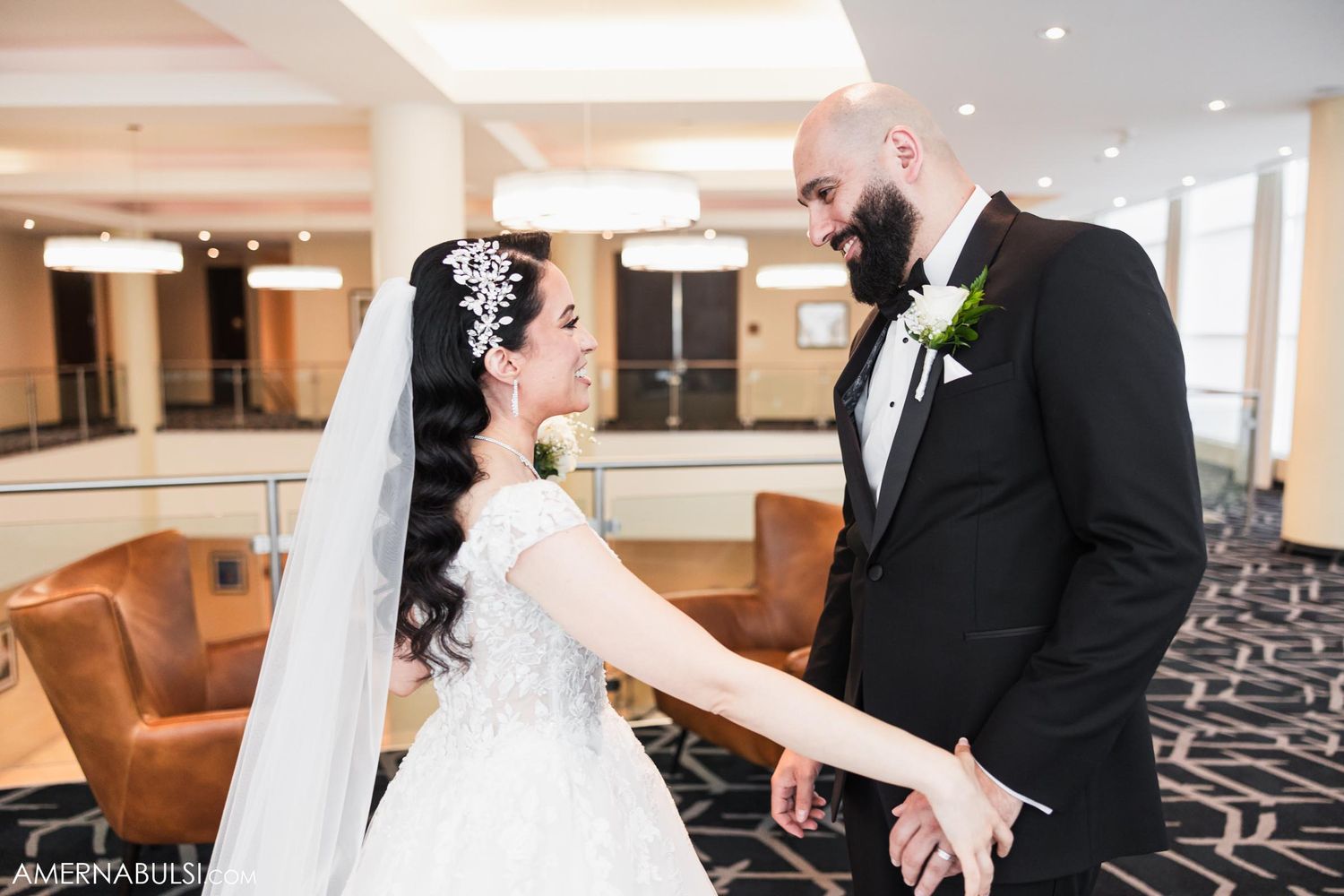 Wedding couple shares intimate moment in hotel lobby with geometric carpet.