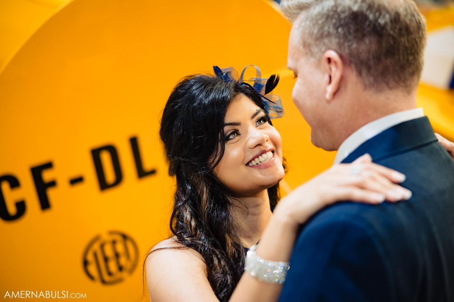 A romantic moment between a couple in formal attire against a bright yellow aircraft backdrop.