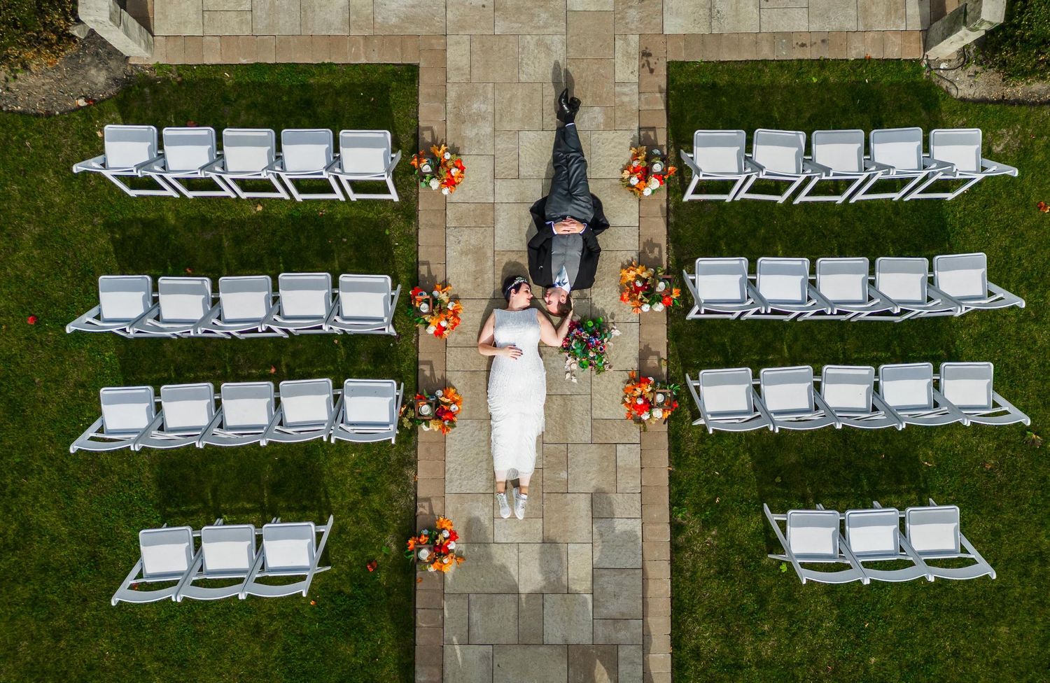 Aerial view of wedding ceremony setup with white chairs arranged symmetrically on lawn.