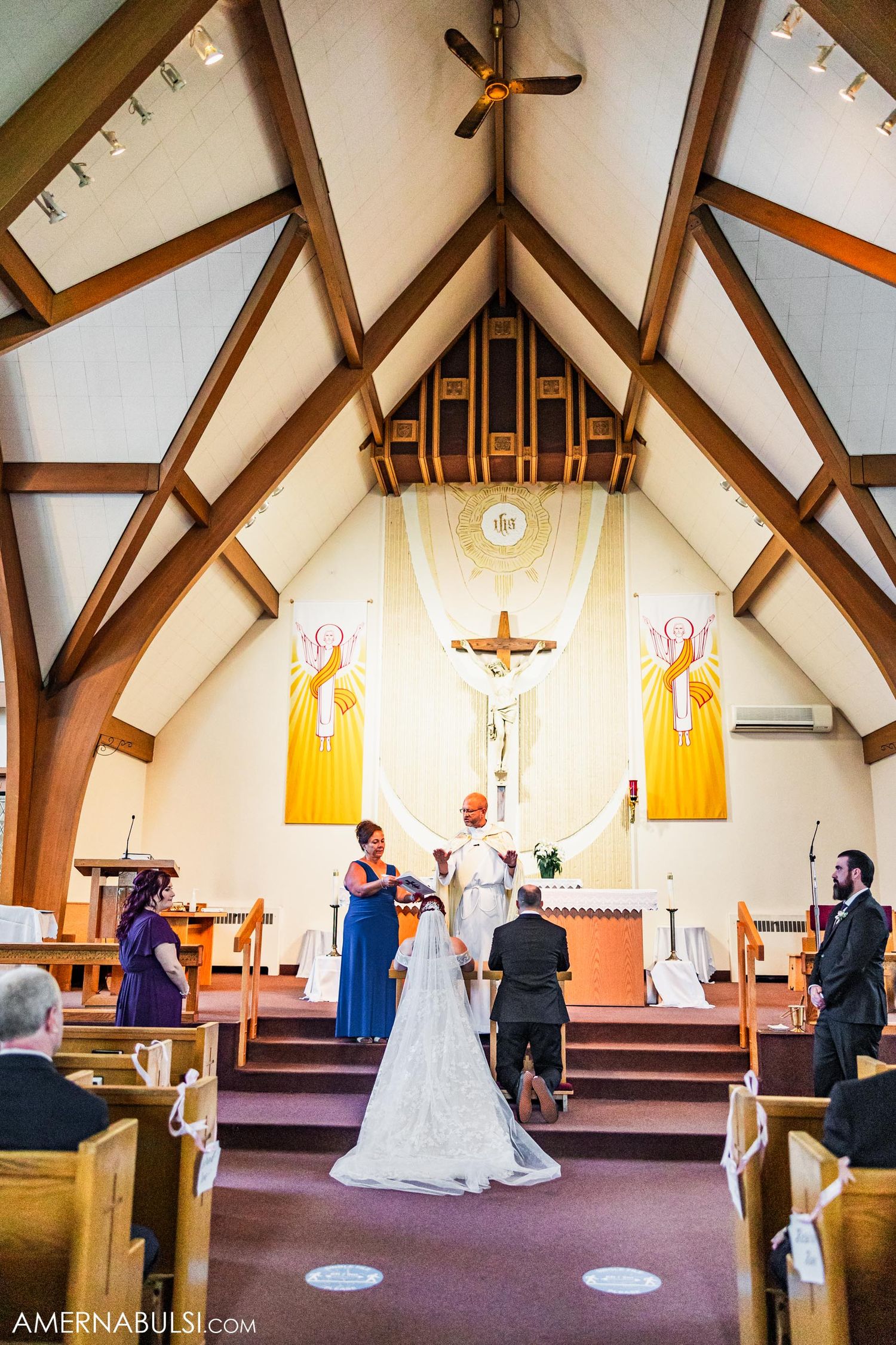 A wedding ceremony takes place in a church with vaulted ceilings and religious artwork.