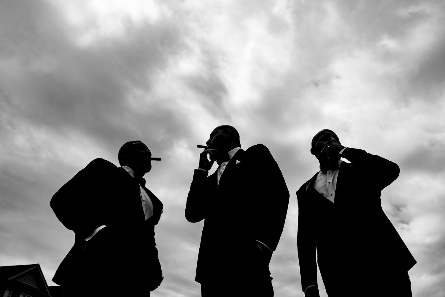Dramatic silhouette of three figures in suits against a cloudy sky.