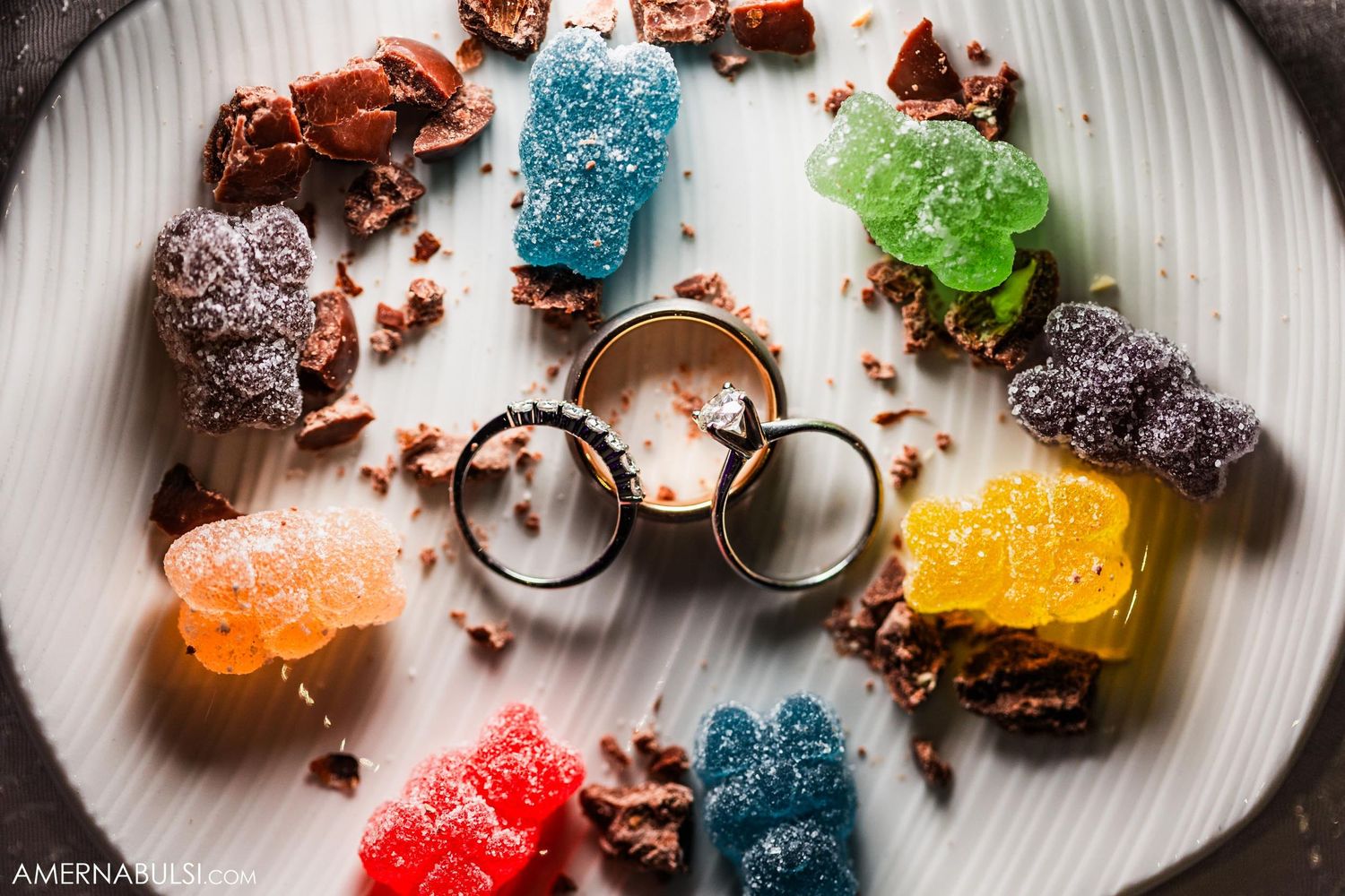 Colorful gummy bears and candies arranged in circle on white plate.