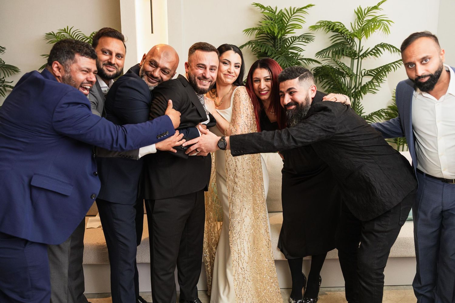 A group of formally dressed guests pose together for a fun group photo at a celebration.